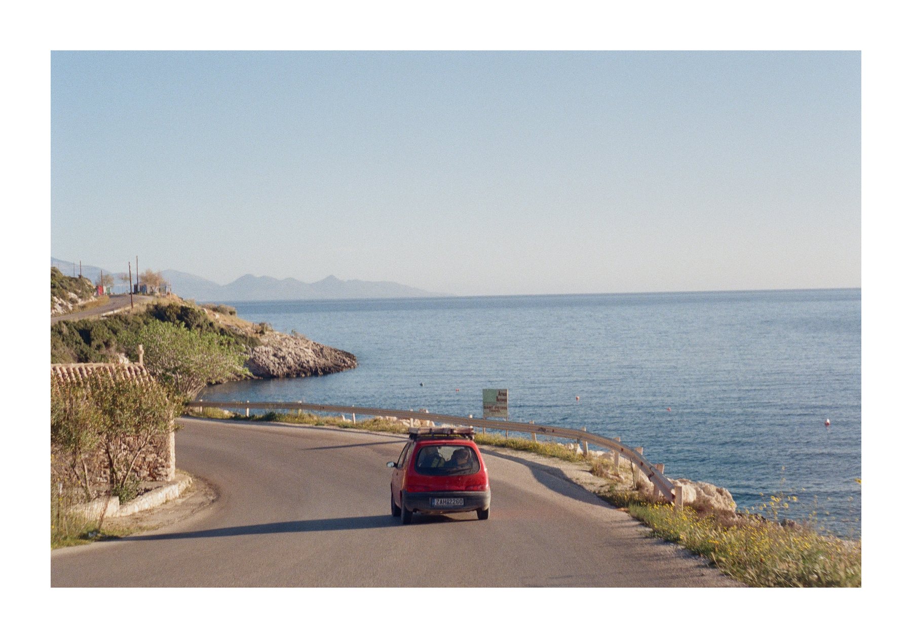Car driving along a coastal road in Greece